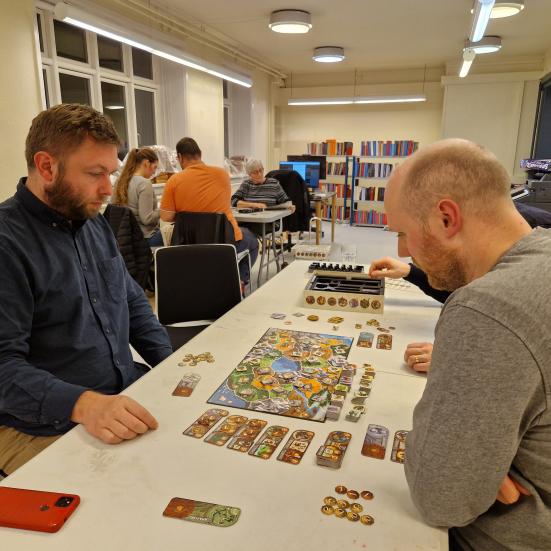 Folk der sidder ved et bord med brætspil
