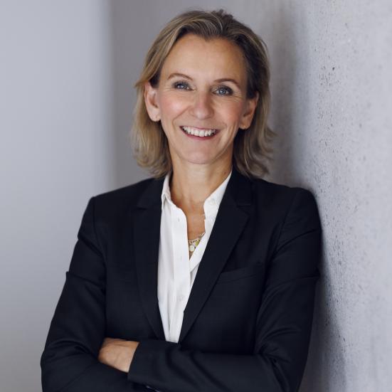 Billedet viser Sofie Rud, der står i en blazer og smiler. Hun har armene over kors.