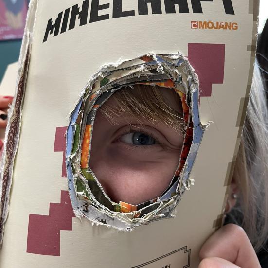 Barn kigger gennem et hul i en bog