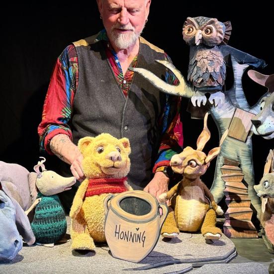 Billedet viser en mand og karaktererne fra Peter Plys bøgerne