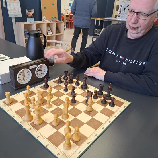 Billedet viser en repræsentant fra Frederikssund Skakforening, som sidder foran et skakbræt på Frederikssund Bibliotek