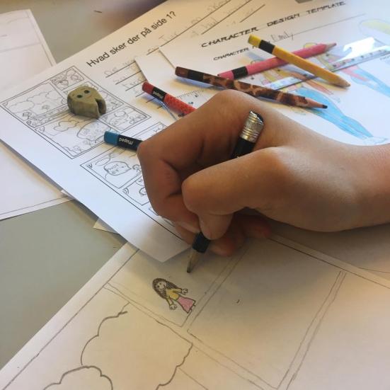Billedet viser en hånd, som tegner en tegneserie