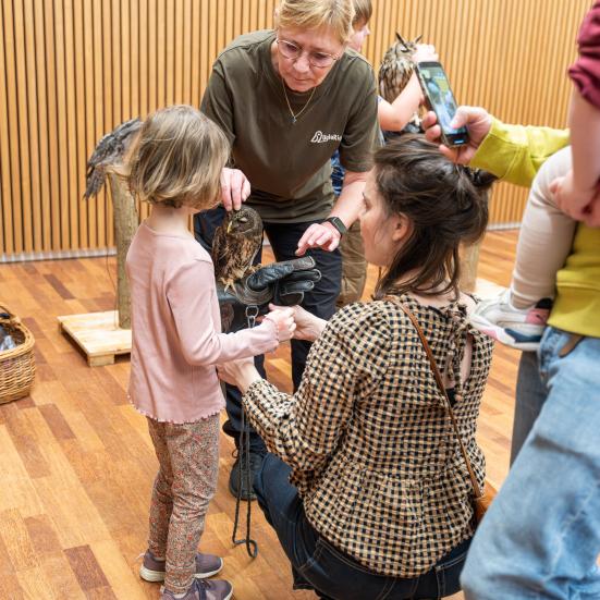 En pige prøvet at holde en ugle på armen