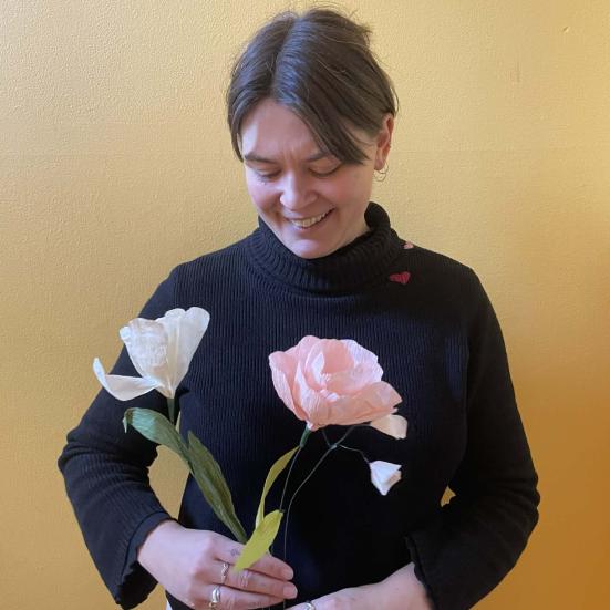 Kvinde står med to papirblomster