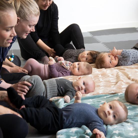 Babyer og mødre hygger på gulvet