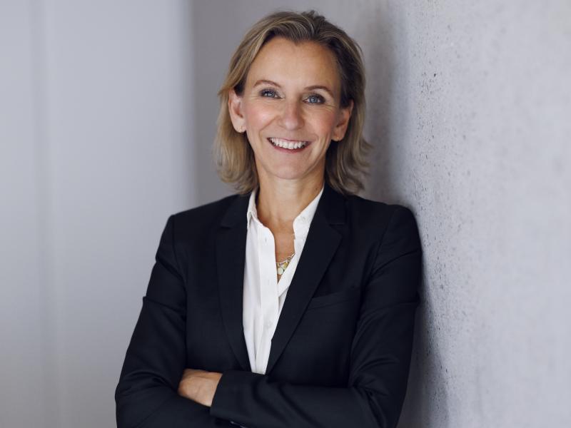 Billedet viser Sofie Rud, der står i en blazer og smiler. Hun har armene over kors.