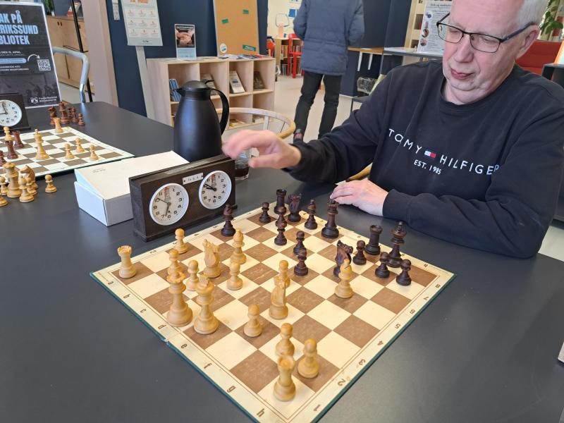 Billedet viser en repræsentant fra Frederikssund Skakforening, som sidder foran et skakbræt på Frederikssund Bibliotek