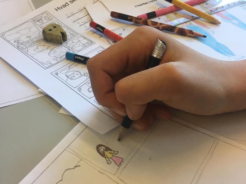 Billedet viser en hånd, som tegner en tegneserie