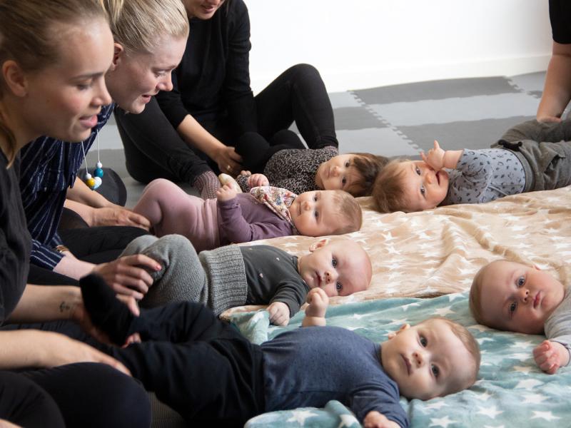 Babyer og mødre hygger på gulvet