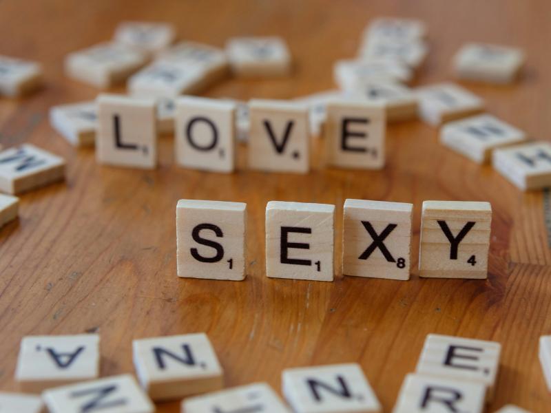 træbord med scrabble bogstaver, som staver love og sexy