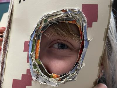 Barn kigger gennem et hul i en bog