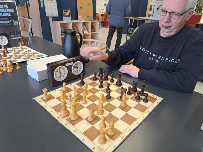 Billedet viser en repræsentant fra Frederikssund Skakforening, som sidder foran et skakbræt på Frederikssund Bibliotek