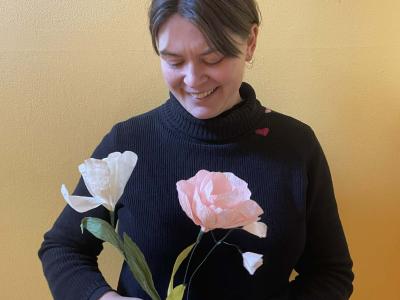 Kvinde står med to papirblomster