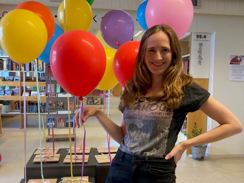 Kvinde med balloner og gaver i baggrunden