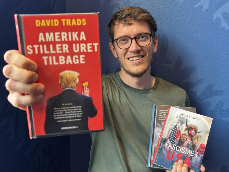 Billedet viser kulturformidler Dennis Odgaard med tre bøger, hvor den ene bog holdes frem mod kammeraet. Bøgerne handlet om USA.