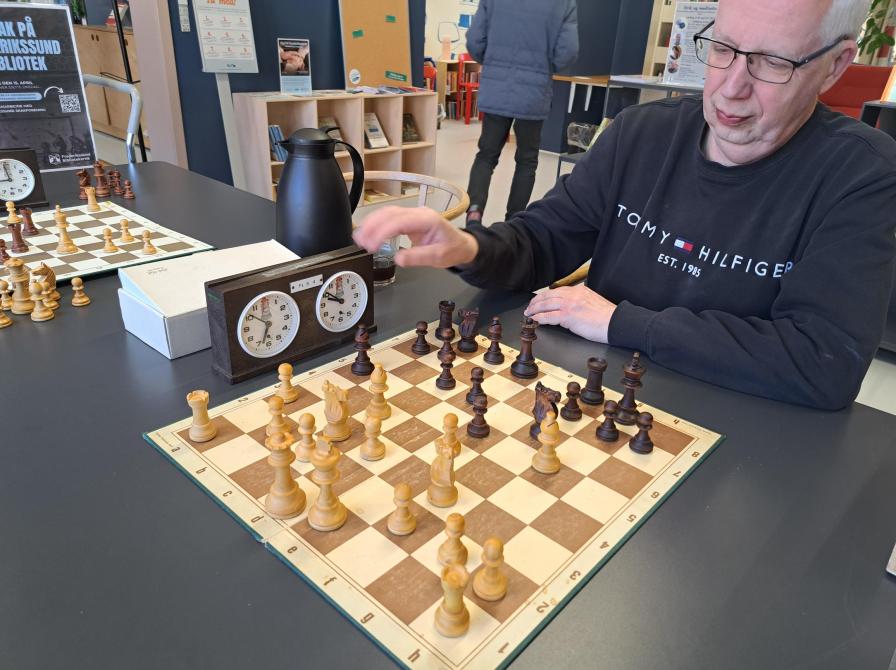 Billedet viser en repræsentant fra Frederikssund Skakforening, som sidder foran et skakbræt på Frederikssund Bibliotek
