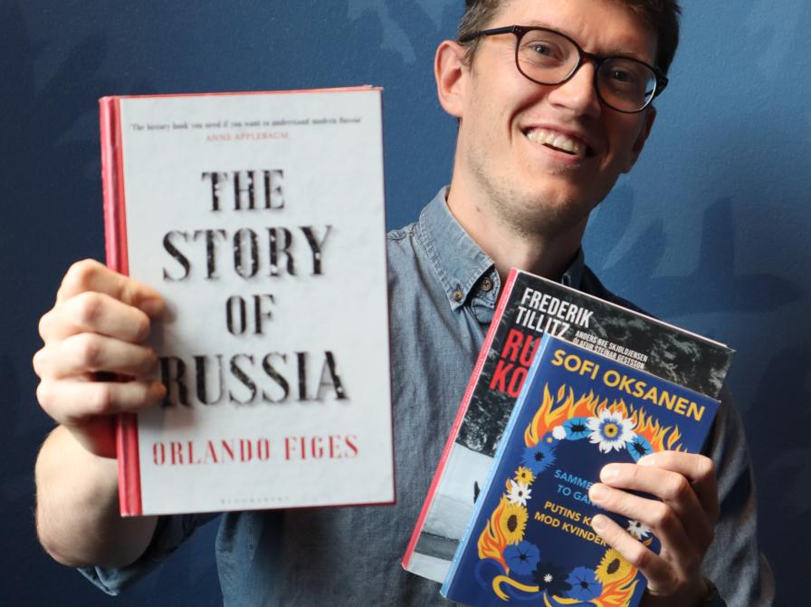 Kulturformidler Dennis Odgaard står og holder tre bøger om Rusland